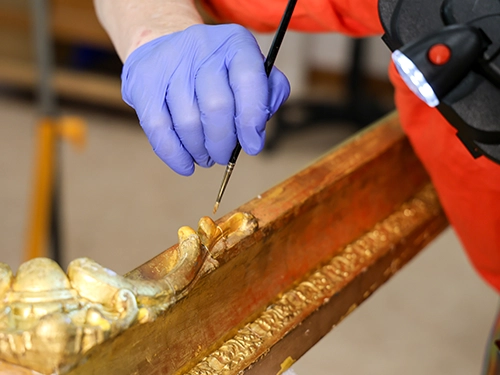 Art conservator restoring gilded frame.