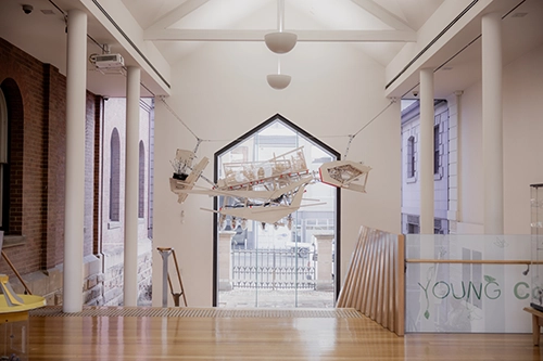 Large suspended artwork inside a bright gallery space.