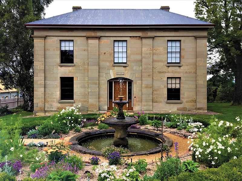 Georgian sandstone house museum with central fountain and formal garden.