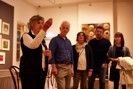 A TMAG tour guide talks to a tour group about art works on show in the gallery