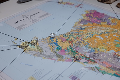 Detailed geological map with small numbered cubes placed across Tasmania.