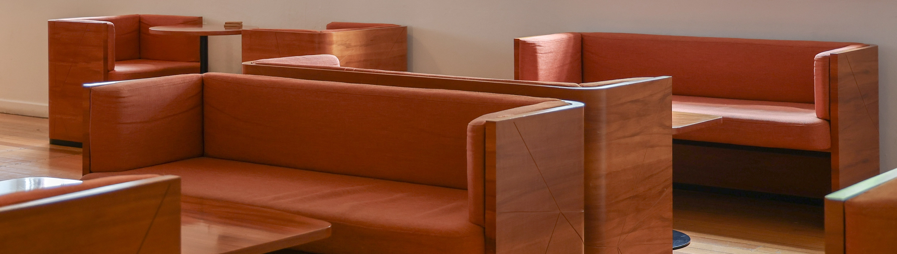 Modern lounge area with timber-framed sofas and warm-toned upholstered seating arranged on polished wooden floors.