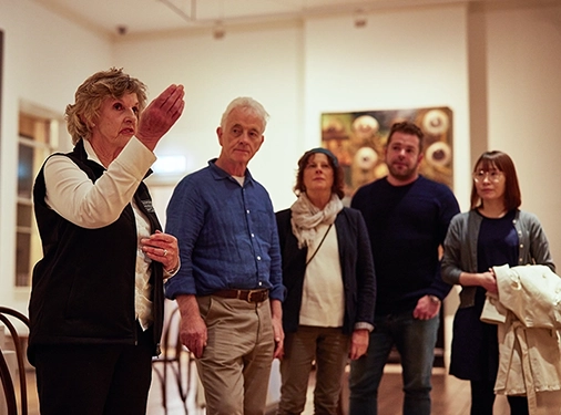Museum guide speaking to a group of visitors in an art gallery.