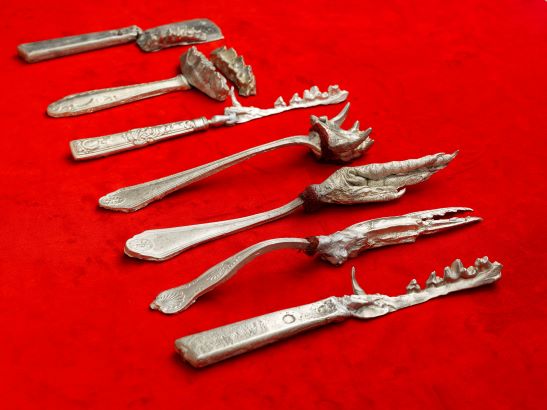 Out of Flavour by Sue Kneebone. A series of unusual looking silver implements set against a red velvet background.